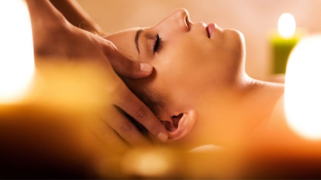 Mujer con los ojos cerrados recibe un masaje energético en el rostro, rodeada de luz cálida. La escena transmite relajación profunda, liberación de tensiones y conexión interior, reflejando la esencia del Curso Estética Energética FlowSkinBody, una experiencia transformadora guiada por la formadora Svit Bytka para activar la energía vital y revelar la belleza desde el movimiento consciente del cuerpo.