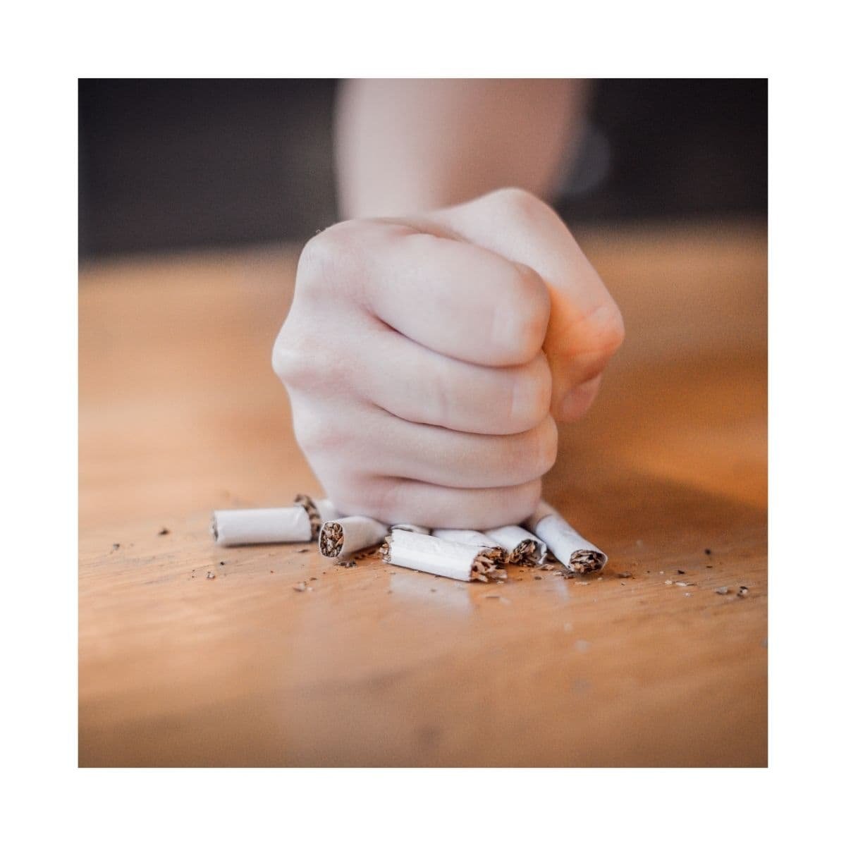 Persona rompiendo cigarrillos sobre una mesa, representación del programa para dejar de fumar con hipnosis